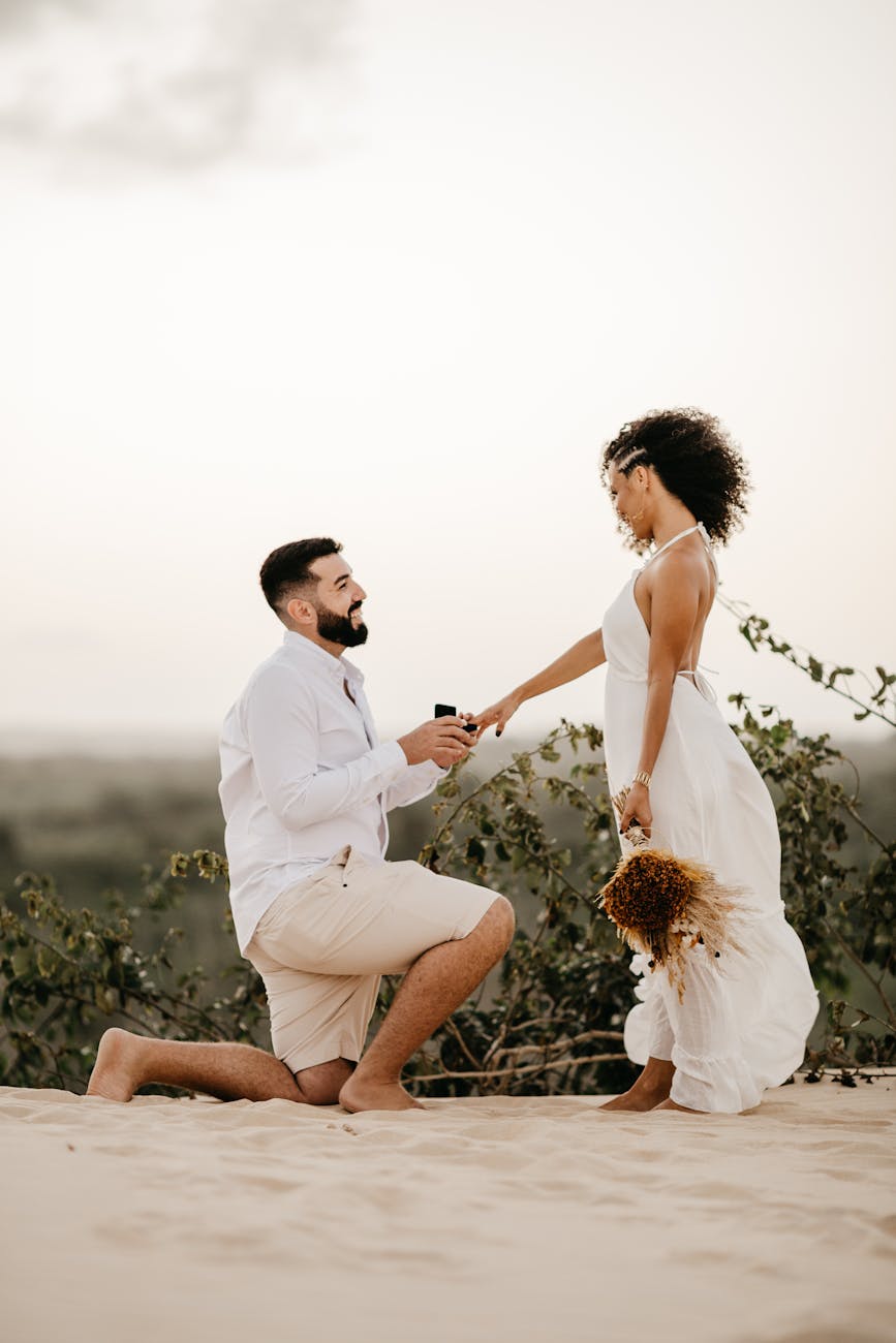 man kneeling and proposing to woman with wedding ring